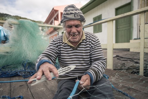 Arreglar las redes lleva mucho tiempo. Con el palo de la boca miden la distancia exacta entre cada nudo.