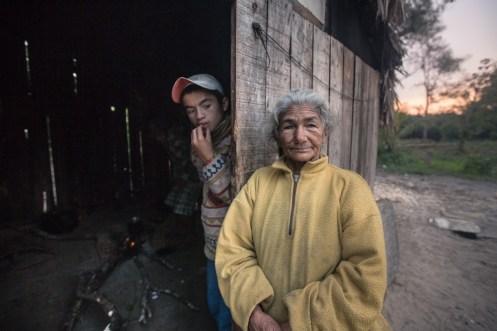 La abuela junto a otro nieto frente al cuarto de hacer fuego. No siempre disponen de gas.