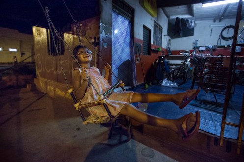 Onieli se balancea en el columpio que su padre Fabio le hizo con palos de escoba viejos.