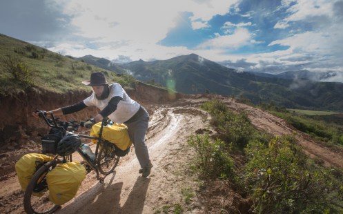 Federico empuja su bicicleta por el barro en uno de los desvíos de la carretera que se encuentra en construcción.